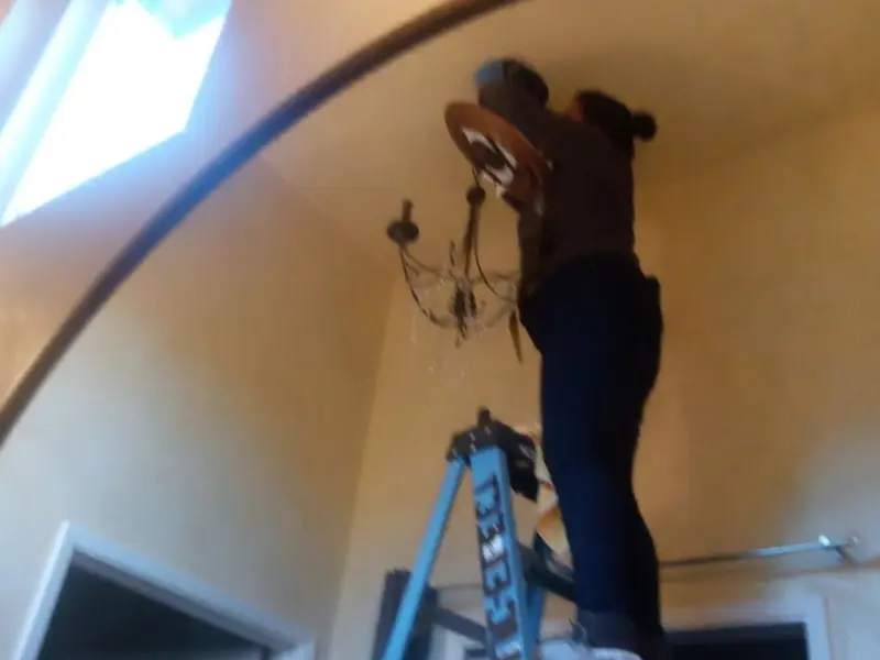 Electrician installing a chandelier in a Lilburn residence